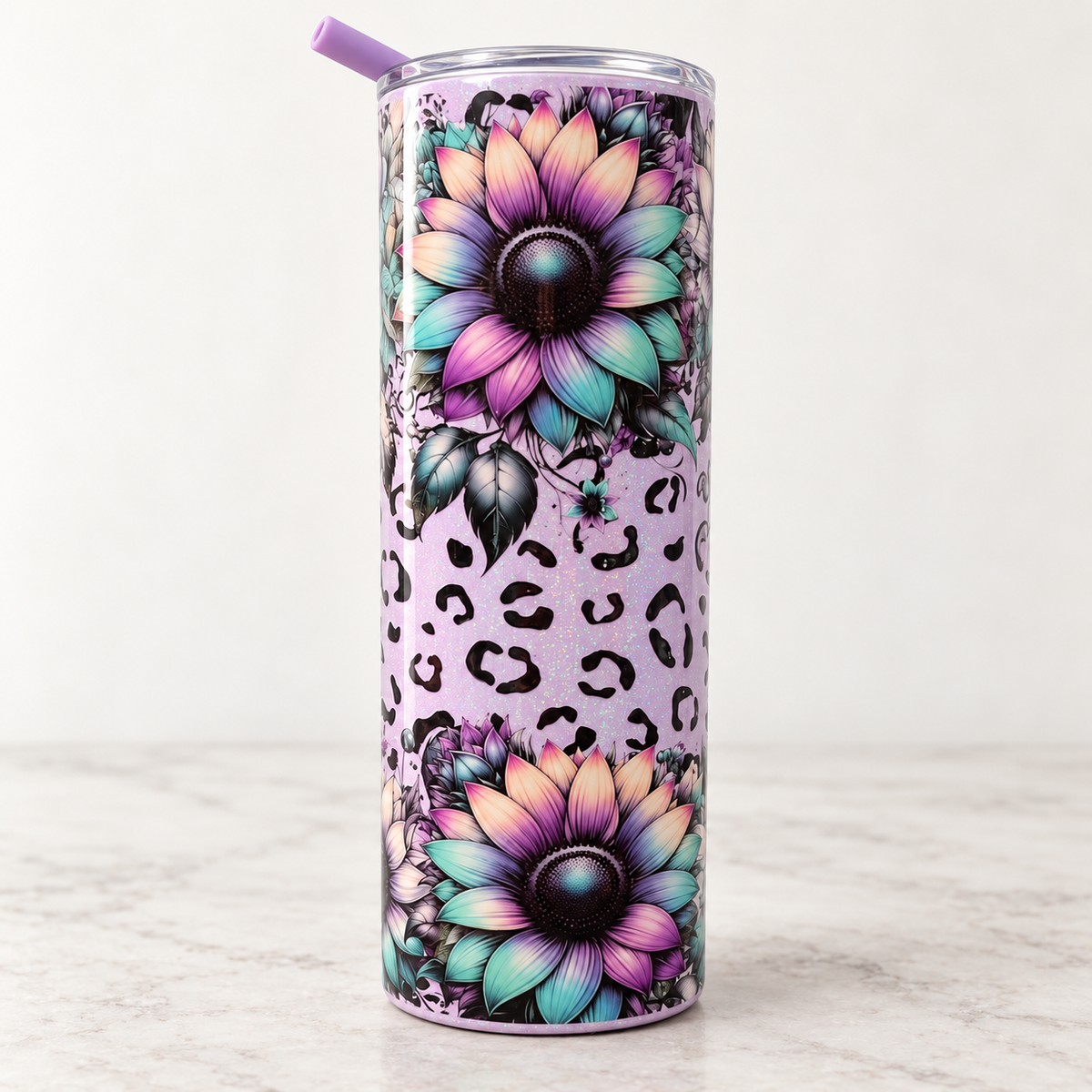 A tall insulated tumbler with a clear lid and purple straw, decorated with two large pastel sunflower designs, black leopard spots, and floral accents on a light lavender background.