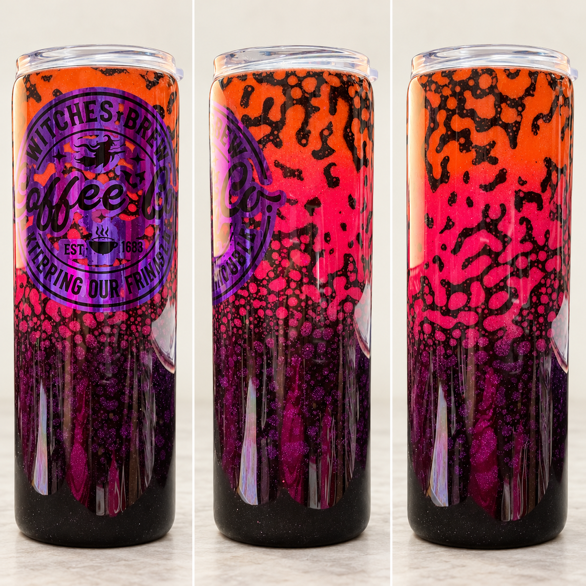 Three tall slim can-style tumblers shown side by side on a light marble surface. The tumblers have a glossy Halloween-themed design with a bright orange-to-pink-to-purple gradient and black splatter/catspots, plus a purple circular logo reading 'Witches Brew coffee' and 'Stirring up trouble"