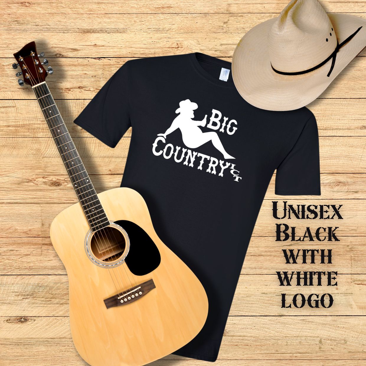 Black t-shirt with white 'Big Country ICT' logo, acoustic guitar, and cowboy hat on a wooden surface.