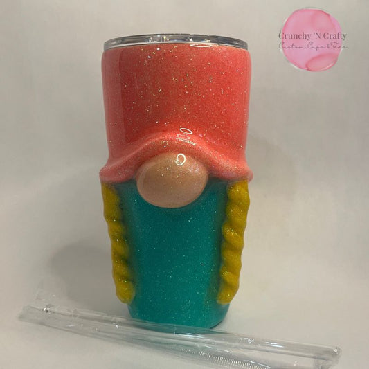 20 ounce curved tumbler with 3d effects added to make it look like a gnome yellow braids, oval nose and coral colored hat with turquoise glitter on the bottom half of the cup 